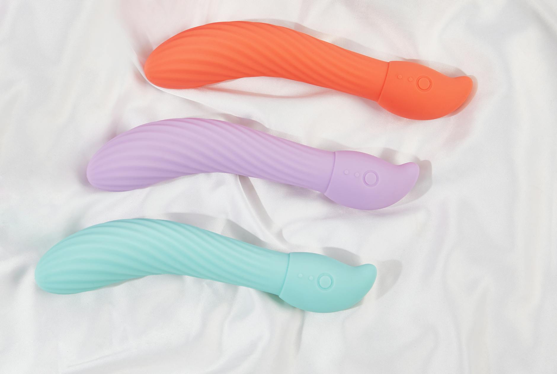 Three colorful lemon clitoral vibrators arranged on white silk fabric