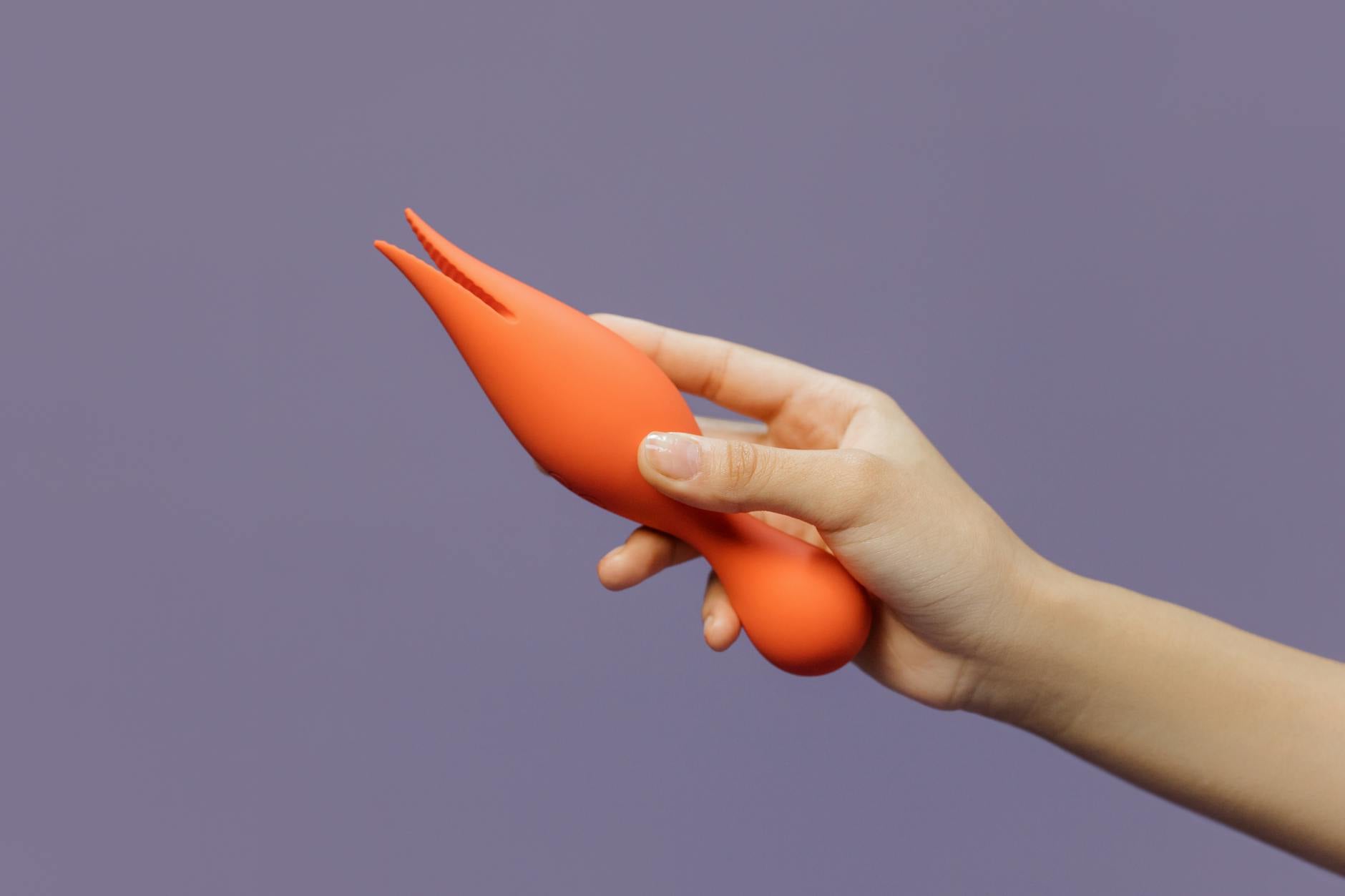 Close-up of a lemon vibrator held in hand against a minimalistic purple backdrop, showcasing modern sensuality
