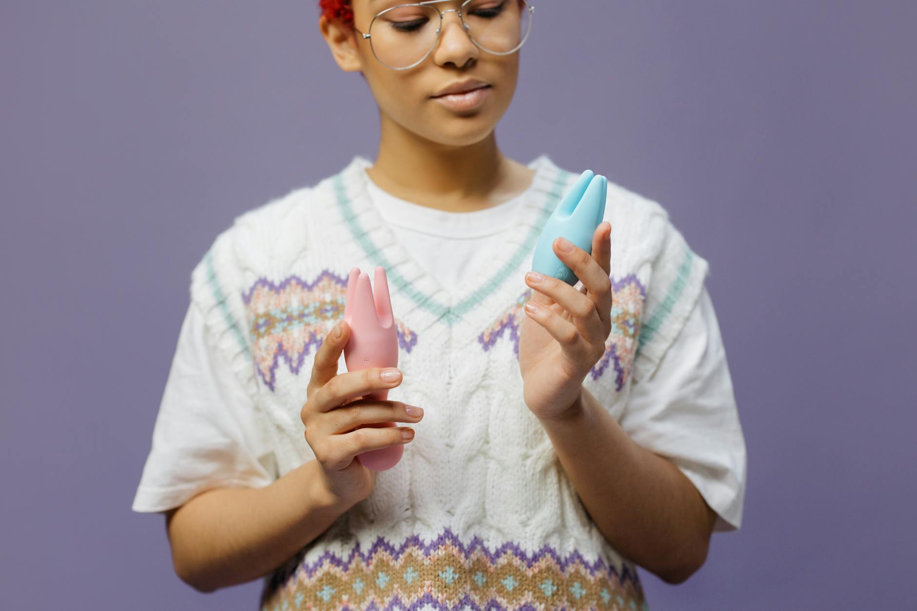 Woman holding silicone clitoral vibrators in a thoughtful pose, representing intimate solo and partnered pleasure