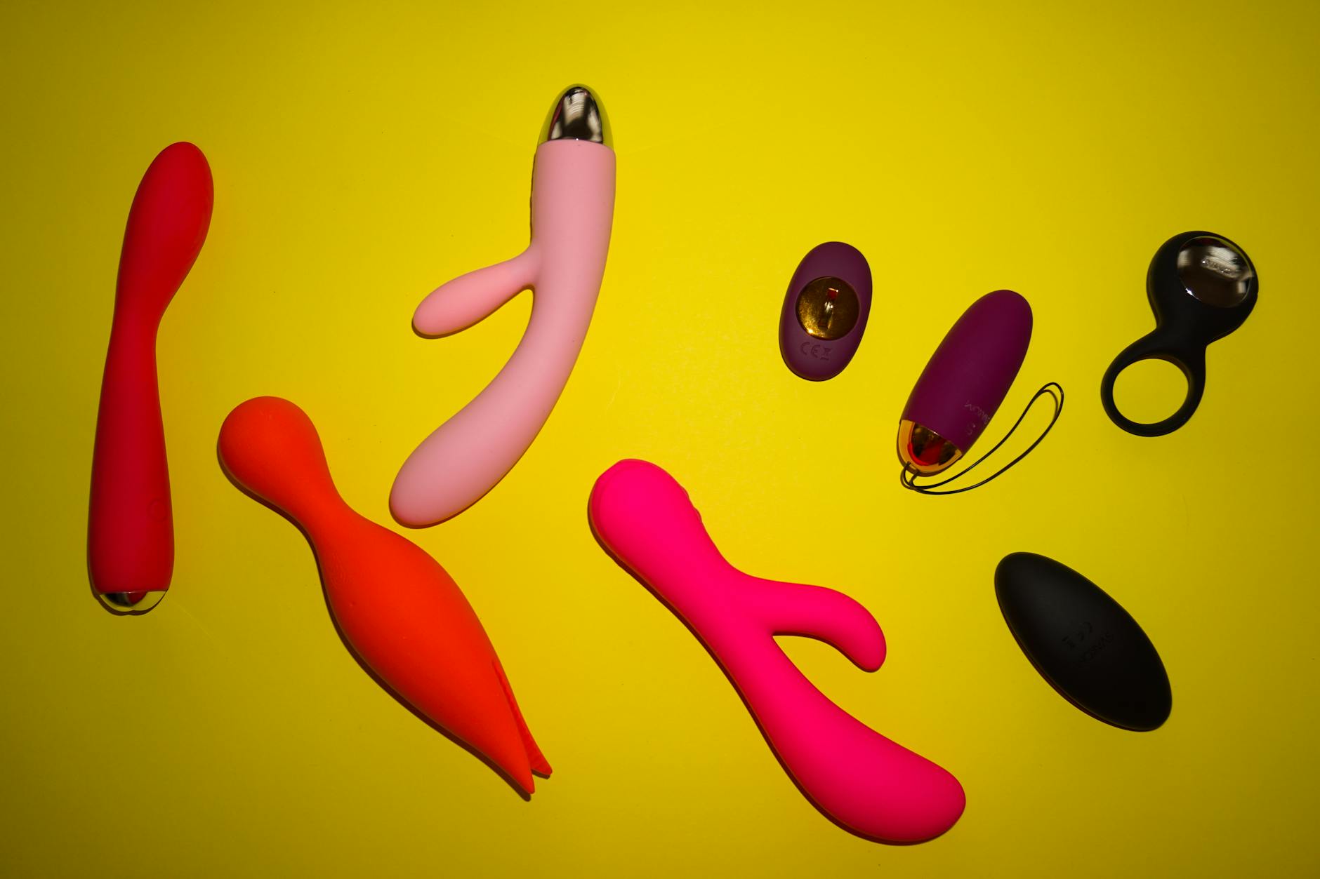 Vibrant collection of colorful lemon vibrators and sex toys arranged on a bright yellow surface